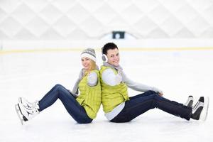 vrolijk paar zittend Aan de het schaatsen baan foto