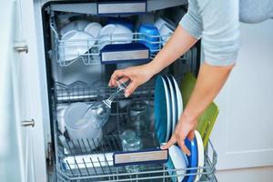 jong vrouw schoonmaak vaatwasser in de keuken foto