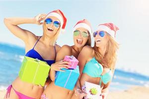 groep van meisjes in santa's hoeden hebben pret Aan de strand foto