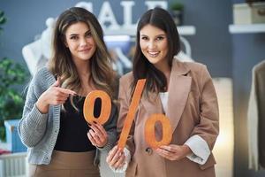 twee meisjes Aan boodschappen doen Holding uitverkoop percentage teken. foto