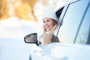 gelukkig vrouw het rijden auto in besneeuwd winter foto