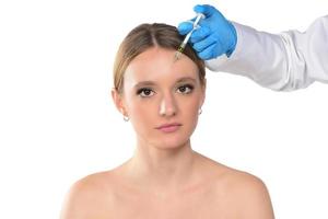 jong vrouw krijgt injectie van botox in haar gezicht. vrouw in schoonheid salon. plastic chirurgie kliniek. foto