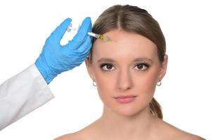 jong vrouw krijgt injectie van botox in haar gezicht. vrouw in schoonheid salon. plastic chirurgie kliniek. foto