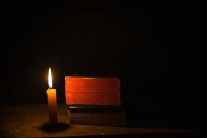 licht kaars met heilig Bijbel en kruis of kruisbeeld Aan oud houten achtergrond in kerk.kaarslicht en Open boek Aan wijnoogst hout tafel Christendom studie en lezing in home.concept van Christus religie foto