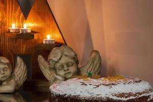 feestelijk Kerstmis opstelling bestaande van lit kaarsen, engel standbeelden en een taart. foto