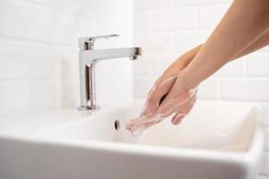 vrouw het wassen haar handen in de badkamer Bij huis foto