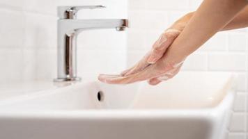 vrouw het wassen haar handen in de badkamer Bij huis foto