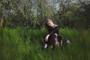 vrouw staren direct en zittend in hoog gras toneel- fotografie foto