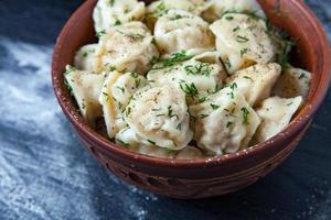 traditioneel Russisch pelmeni of ravioli, knoedels met vlees Aan hout zwart achtergrond. Russisch voedsel en Russisch keuken concept. foto