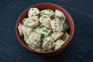 traditioneel Russisch pelmeni of ravioli, knoedels met vlees Aan hout zwart achtergrond. Russisch voedsel en Russisch keuken concept. foto