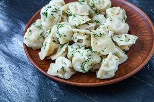 traditioneel Russisch pelmeni of ravioli, knoedels met vlees Aan hout zwart achtergrond. Russisch voedsel en Russisch keuken concept. foto