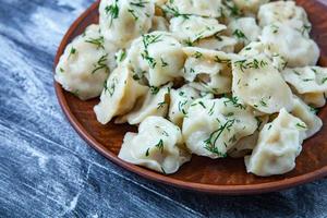 traditioneel Russisch pelmeni of ravioli, knoedels met vlees Aan hout zwart achtergrond. Russisch voedsel en Russisch keuken concept. foto