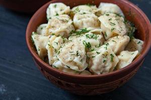 traditioneel Russisch pelmeni of ravioli, knoedels met vlees Aan hout zwart achtergrond. Russisch voedsel en Russisch keuken concept. foto