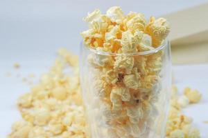 boterachtig popcorn geplaatst in een Doorzichtig glas en verspreide Aan een wit achtergrond foto