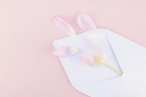 roze tulp met bloemblaadjes in geopend papier envelop foto