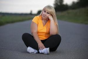 portret van een Europese middelbare leeftijd vrouw in een trainingspak, poseren voor de camera, ontspannend. opgewonden te zwaar vrouw in modieus trainingspak resting na oefenen. foto