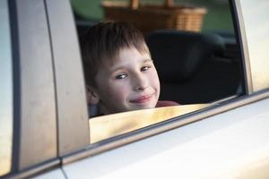 kind in de auto. een weinig jongen looks uit van de auto venster. foto