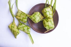 ketupat in aardewerk bord geïsoleerd Aan wit achtergrond. ketupat rijst- knoedel is voedsel geserveerd wanneer idhul fitri eid mubarak in Indonesië, gemaakt van rijst- verpakt in jong kokosnoot bladeren janur foto