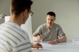 echt professioneel Mens overleg plegen cliënt in kantoor. twee Mannen hebben ontmoeting, maken bedrijf gesprek. verzekeraar geven het advies, manager maken bieden. mentor onderwijs intern. baan interview. foto