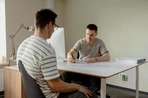 echt professioneel Mens overleg plegen cliënt in kantoor. twee Mannen hebben ontmoeting, maken bedrijf gesprek. verzekeraar geven het advies, manager maken bieden. mentor onderwijs intern. baan interview. foto