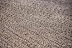 rij in een ploegveld voorbereid voor het planten van gewassen in het voorjaar - geploegd veld met vrachtwagen op het platteland van landbouwbedrijven foto