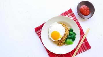 ogenblik noedels geserveerd met ei gebakken en mosterd Groenen Aan bord. ogenblik gebakken noodle indomie foto