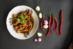 pittig kip voeten met selderij, Chili, ui, knoflook geserveerd met een wit bord geïsoleerd van een zwart achtergrond. foto