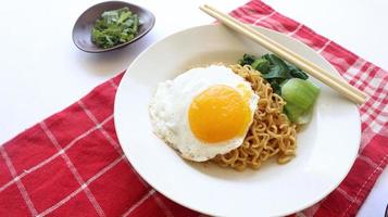 ogenblik noedels geserveerd met ei gebakken en mosterd Groenen Aan bord. ogenblik gebakken noodle indomie foto