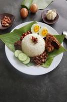 nasi lemak, is traditioneel Maleis gemaakt gekookt eieren, bonen, ansjovis, Chili saus, komkommer. van schotel geserveerd Aan een banaan blad foto