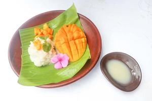 mango kleverig rijst- is Thais toetje gemaakt van kleverig rijst, mango en kokosnoot melk. geïsoleerd Aan wit achtergrond foto