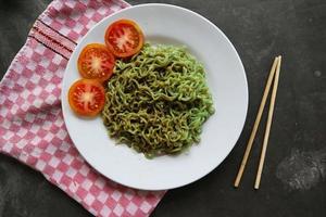 groen noedels, of spinazie pasta , courgette rauw veganistisch pasta duik, en tomaten Aan bord. foto