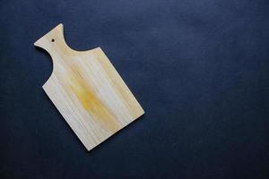 snijdend bord van hout voor Koken. houten snijdend bord Aan zwart achtergrond. top visie met kopiëren ruimte voor tekst. menu, recept, vlak leggen model, banier achtergrond foto