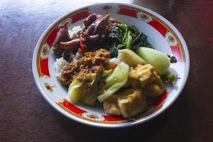 nasi tempong of sego tempong is traditioneel voedsel van banyuwangi, Indonesië gemaakt van rijst, traditioneel gebakken inktvis, gebakken aubergine, komkommer plakjes, groenten, spinazie en pittig sambal Chili foto