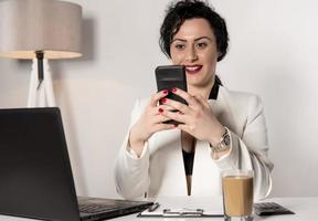 mooi bedrijf vrouw zittend in haar kantoor en pratend Aan de mobiele telefoon. bedrijf concept foto