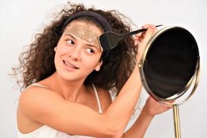 schoonheid procedures huid zorg concept. jong vrouw toepassen gelaats grijs modder klei masker naar haar gezicht foto