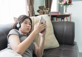 Aziatisch vrouw luisteren muziek- van mobiel telefoon foto