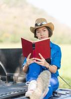 vrouw slijtage hoed en lezing de boek Aan oppakken vrachtauto foto