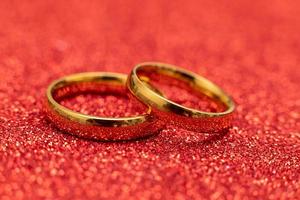 zullen u trouwen mij. twee gouden bruiloft ringen Aan rood schitteren achtergrond. verloving huwelijk voorstel bruiloft concept. st. Valentijnsdag dag ansichtkaart. banier Aan valentijnsdag dag. kopiëren ruimte. foto