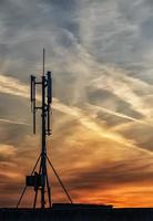 silhouet van gsm zenders Aan de dak kantoor gebouw Bij verbazingwekkend wolken foto