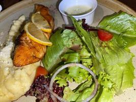 gerookt gegrild Zalm vis geserveerd met salade en puree aardappelen met citroenen foto