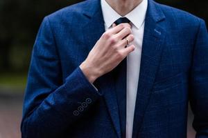 elegant Mens koppelverkoop zijn stropdas over- zwart shirt. aanpassen binden. zwart en paars. jong bedrijf Mens dressing, geïsoleerd Aan zwart achtergrond. bruidegom aanpassen zijn binden. foto