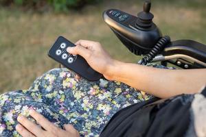 Aziatische dame vrouw patiënt op elektrische rolstoel met joystick en afstandsbediening op verpleegafdeling ziekenhuis, gezond sterk medisch concept foto