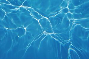onscherp wazig transparant blauw gekleurde Doorzichtig kalmte water oppervlakte structuur met spatten en bubbels. modieus abstract natuur achtergrond. water golven in zonlicht met bijtende middelen. blauw water stralend foto
