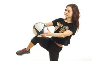 een jong energiek meisje in zwart sportkleding houdt Aan knie voetbal bal foto