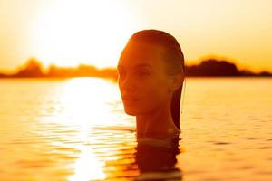 seksueel jong dame in de zee Bij warm zonsondergang foto