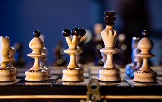schaak bord met schaak stukken Aan blauw achtergrond. concept van bedrijf ideeën en wedstrijd en strategie ideeën. wit koning en koningin dichtbij omhoog. foto
