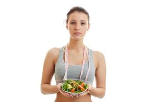 mooi vrouw met meten plakband Aan haar nek eet salade foto