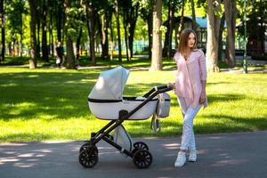 jong mam wandelingen met wandelwagen in de park foto