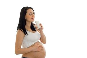 studio portret van jong zwanger brunette vrouw met bril van melk in haar handen geïsoleerd Aan wit achtergrond foto