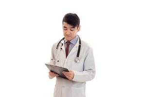een jong dokter in een wit laboratorium jas met een stethoscoop en op zoek Bij tablet geïsoleerd Aan wit achtergrond foto